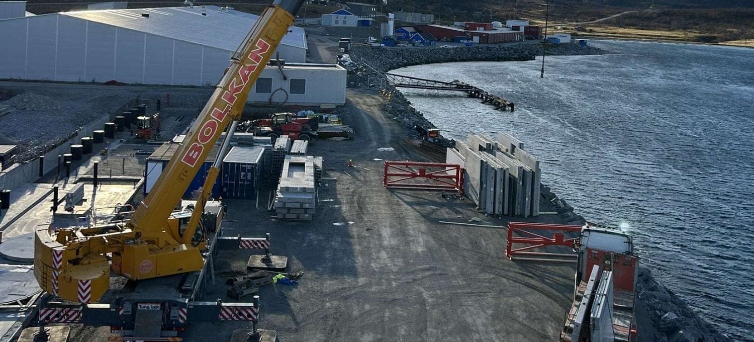 Bolkan mobilkran med bommen ute på anlegget ved sjøen i Adamselv, med betongelementer og fjell i bakgrunnen