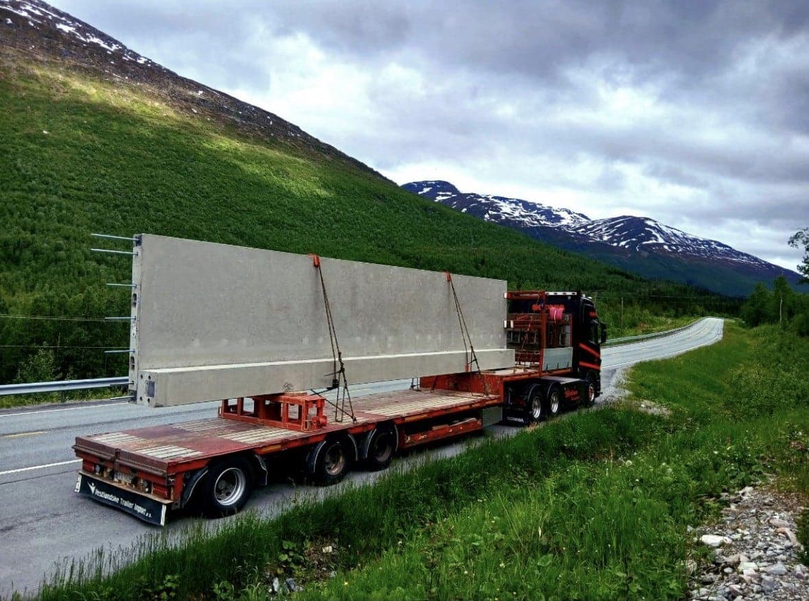 Langt betongelement sikret på uttrekkshenger langs en fjellvei