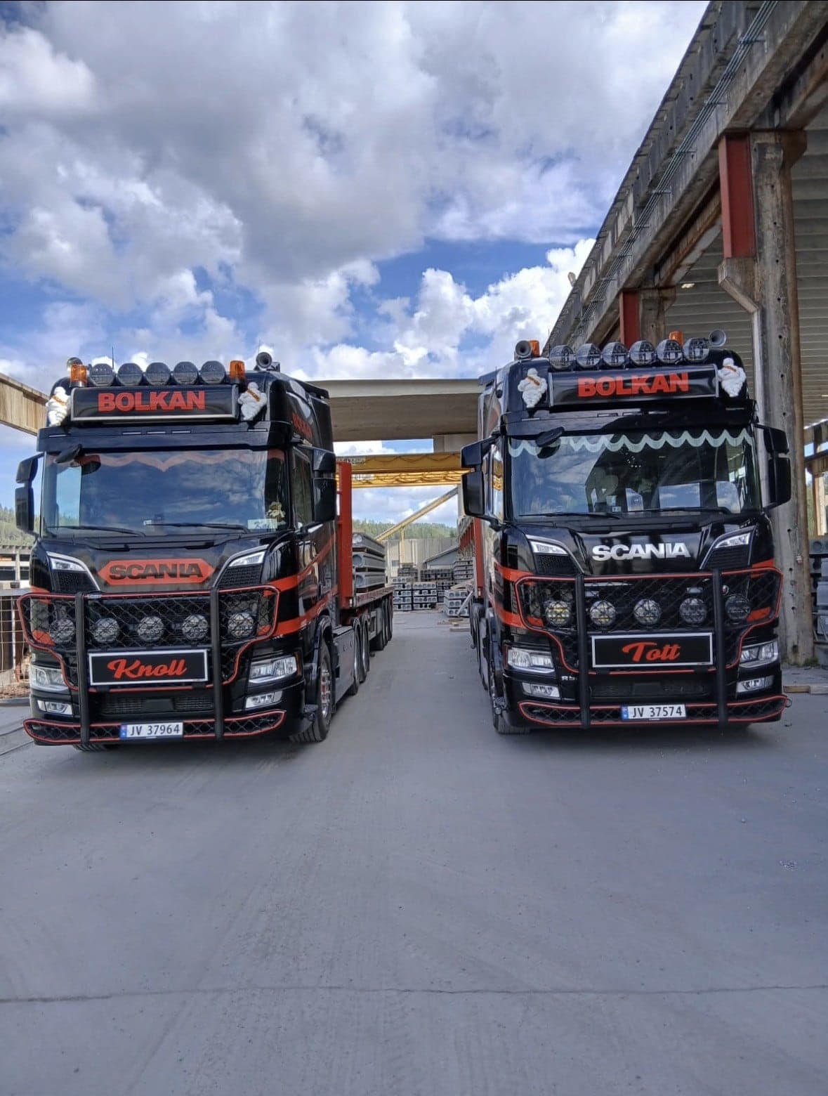 To svarte Bolkan Scania side om side ved en elementfabrikk