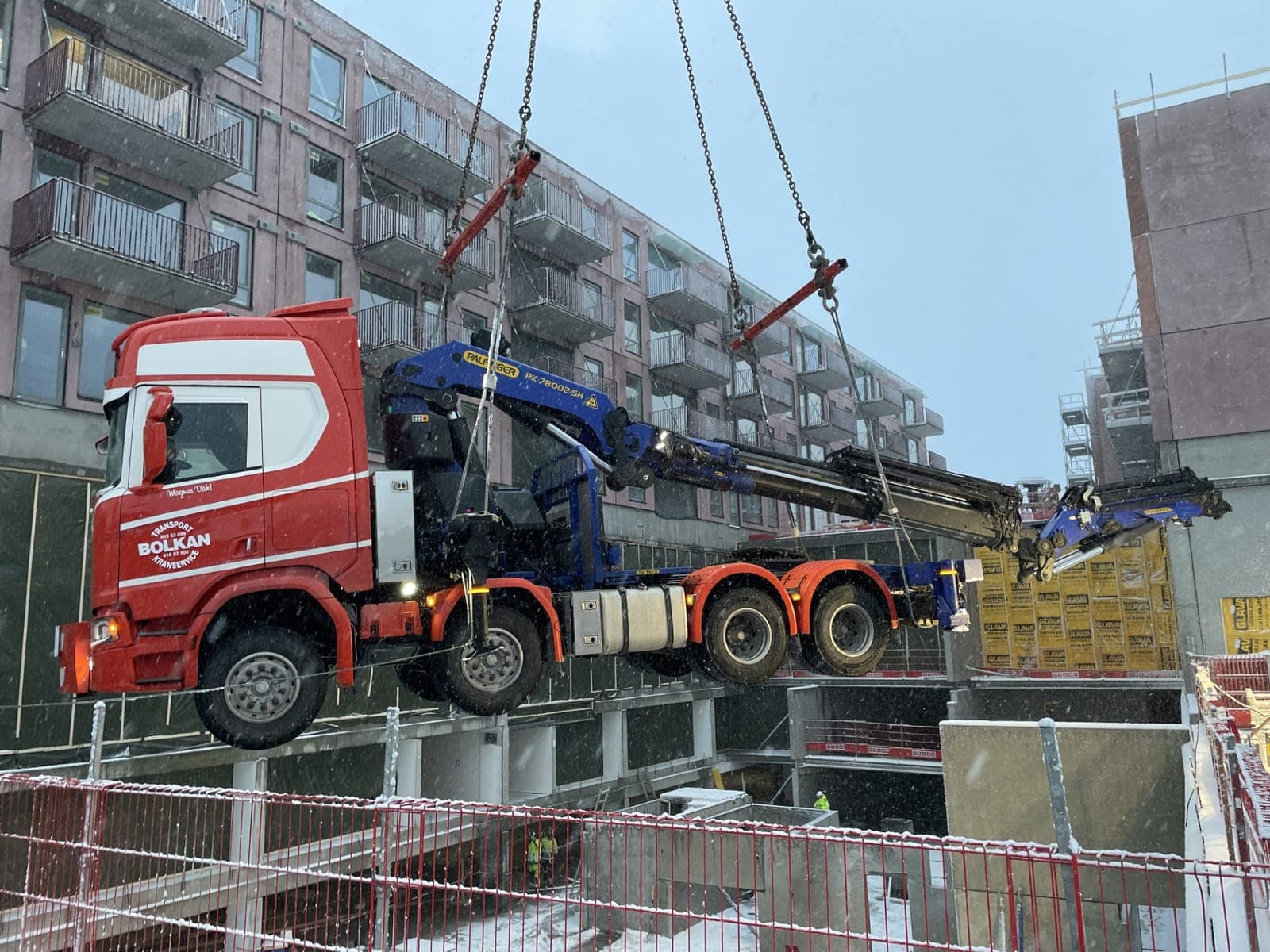 Bolkans kranbil henger i en kran og løftes ned i kjelleren på et nytt leilighetsbygg i Trondheim