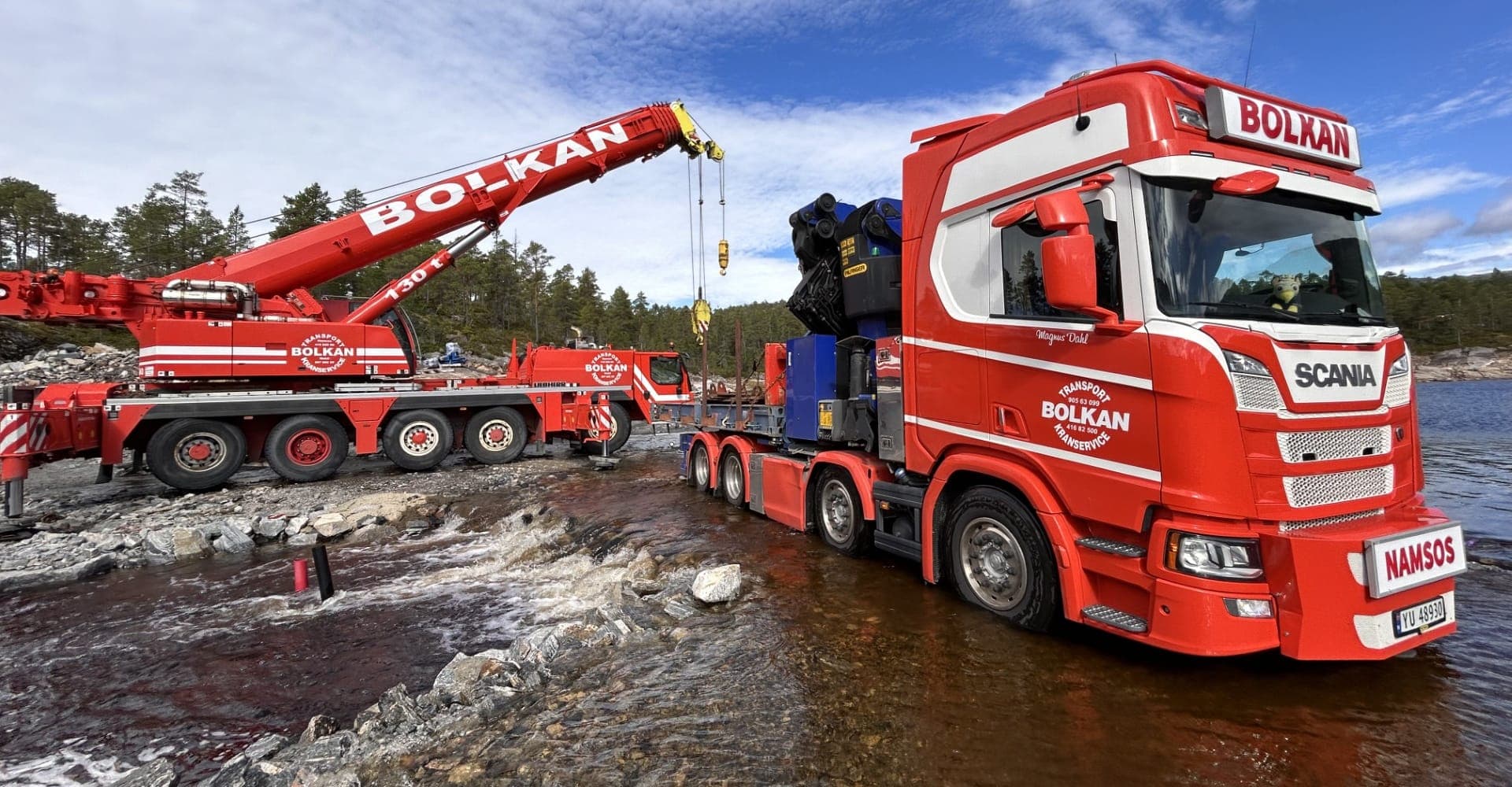Bolkans kransemi, en rød Scania med Palfinger-kran, står i elvekanten med 130-tonns mobilkran bak