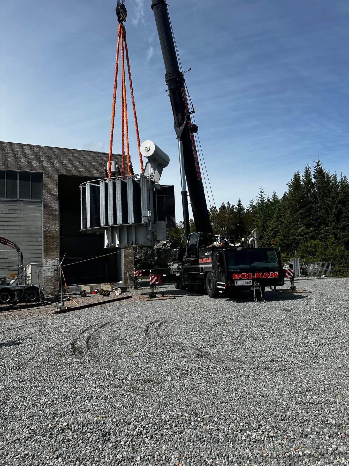 Bolkans Liebherr LTM 1160 løfter en generator på plass ved et bygg