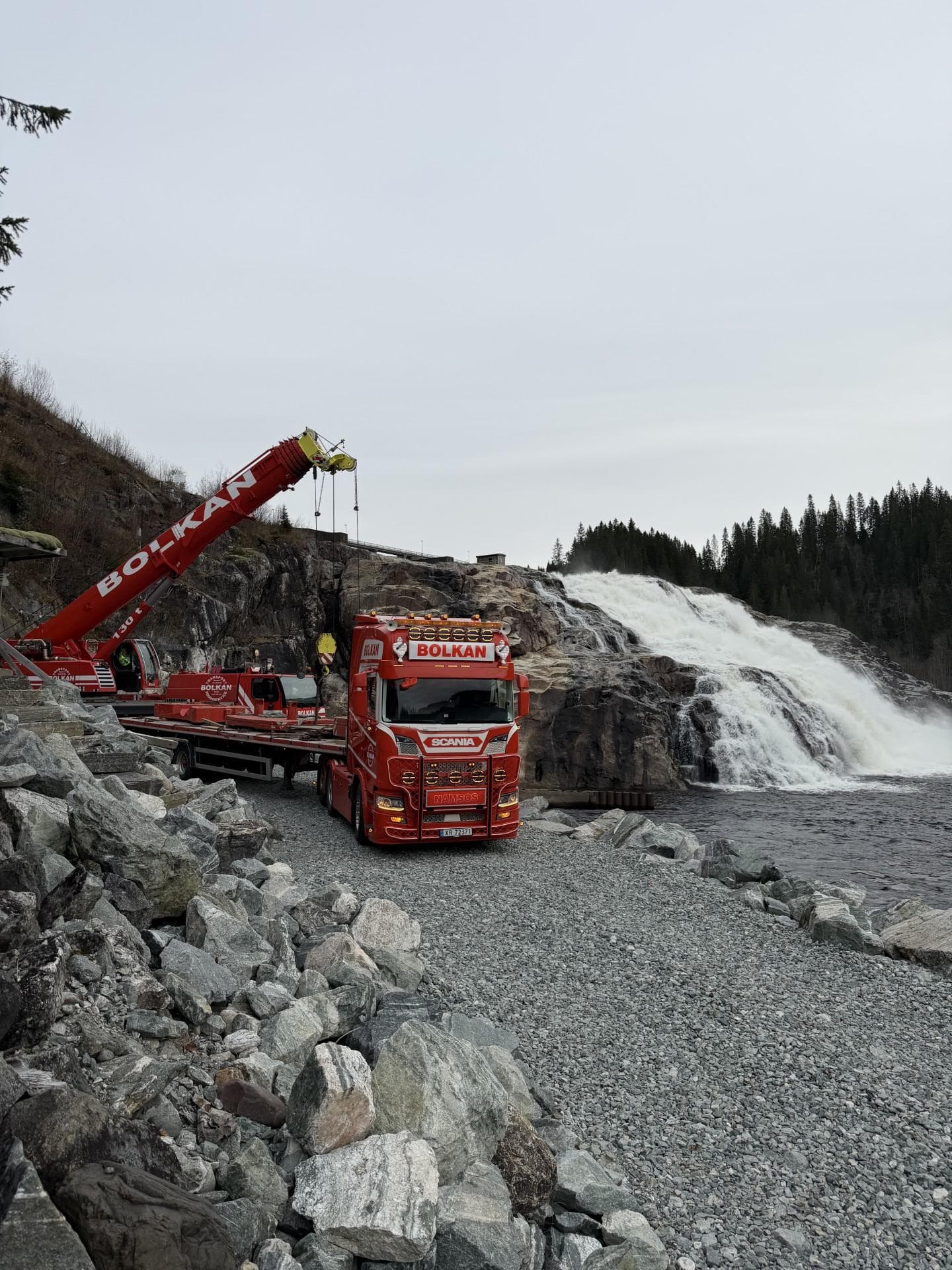 Bolkans 130-tonns mobilkran rigget opp ved en foss, med Scania som har fraktet motvekten