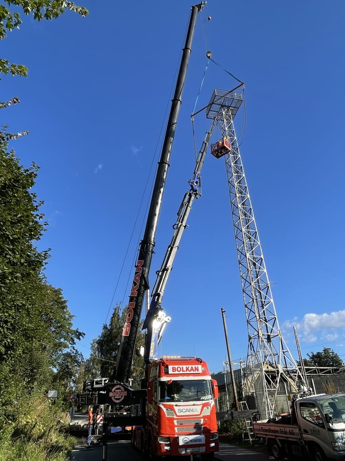Bolkan mobilkran og kranbil tar ned en høy gittermast ved jernbanen i Trondheim