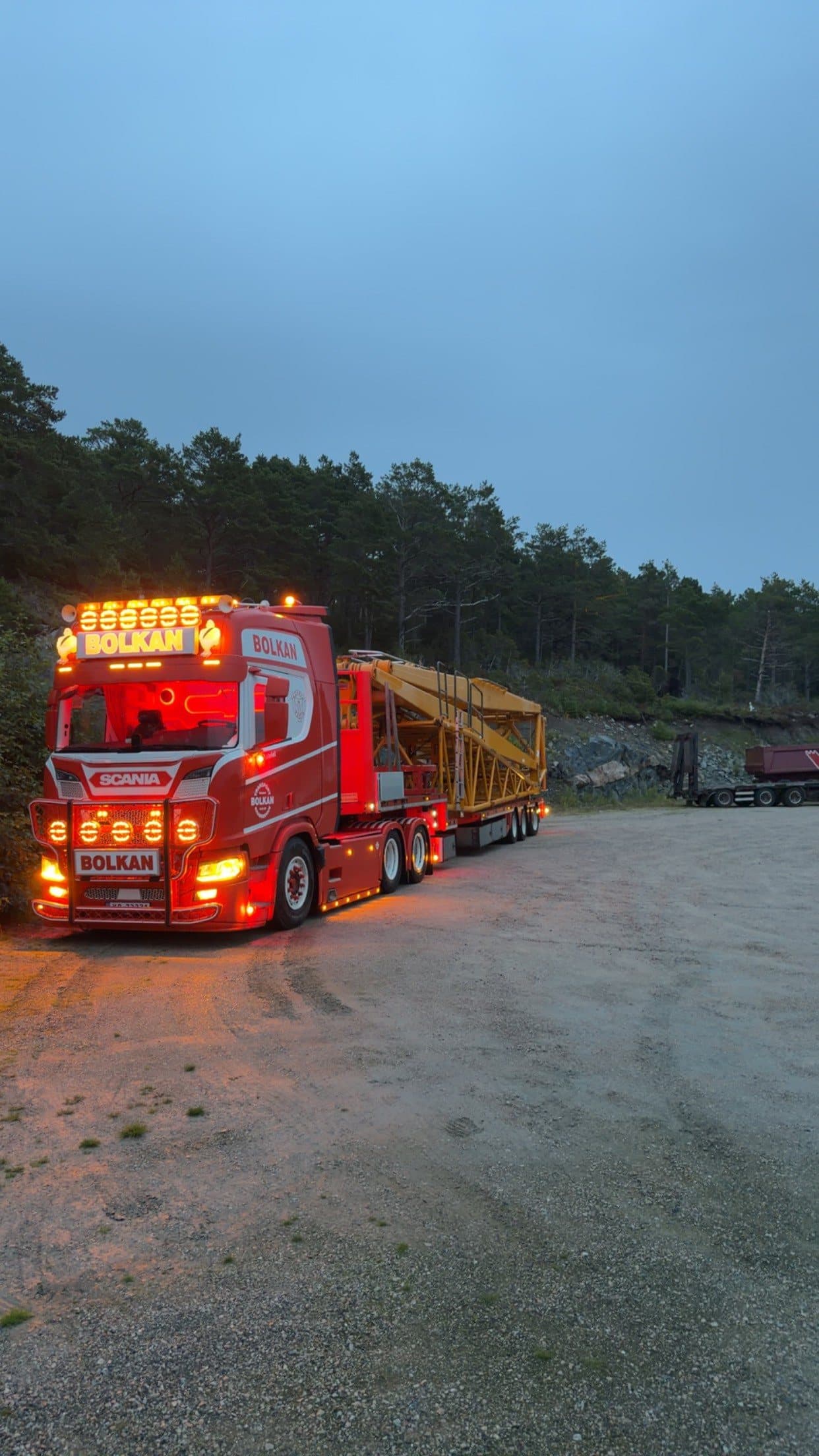 Bolkan Scania med beltekrandeler på hengeren i skumringen